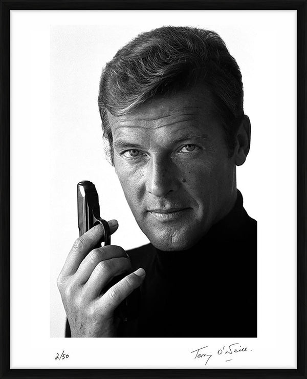 Roger Moore as James Bond poses with his weapon of choice, December 1972 — Limited Edition Print, framed - Terry O'Neill